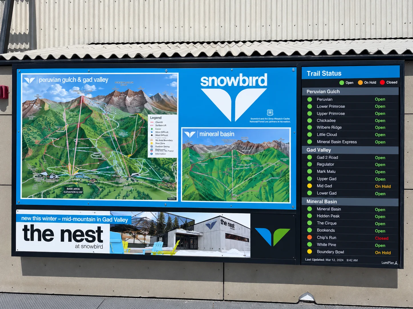 An on-mountain display at Snowbird showing the trail map beside a live Trail Status board listing runs in Peruvian Gulch, Gad Valley, and Mineral Basin as Open, On Hold, or Closed, last updated at 9:42 AM